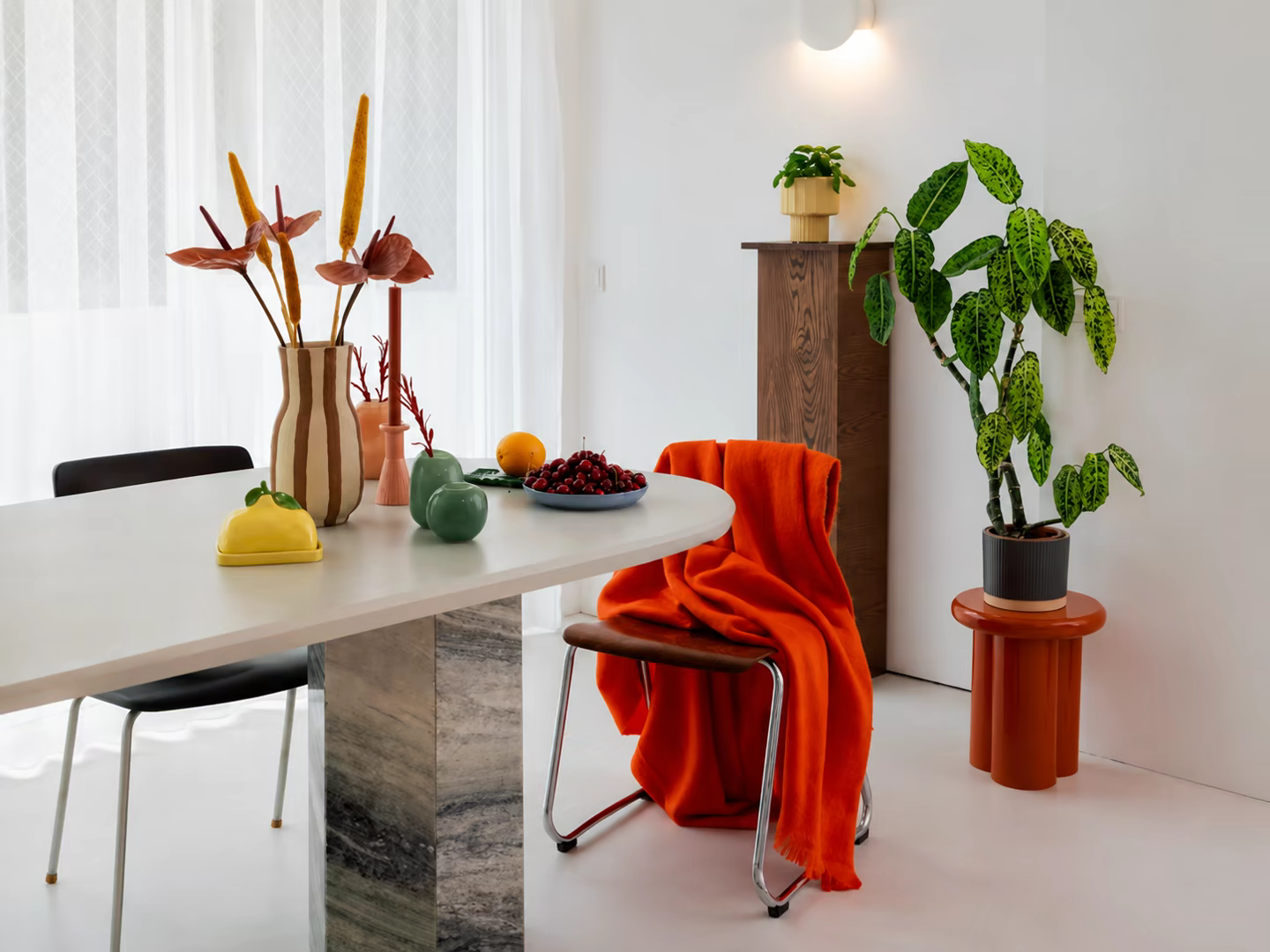 Styled dining space with colourful accessories, plants, and textiles